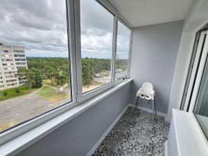 um quarto branco com janelas e uma cadeira branca em Ventspils Luxury Sunset View Apartments em Ventspils