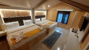 a large room with two beds and a television at Hotel Outlook - Pahalgam in Pahalgām