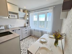 uma cozinha com uma mesa com copos e flores em Ventspils Luxury Sunset View Apartments em Ventspils