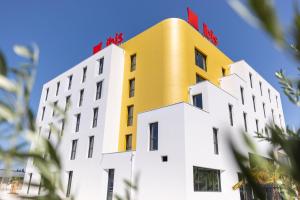 um edifício com um top amarelo em cima em Ibis Marseille Marignane Technopole em Marignane