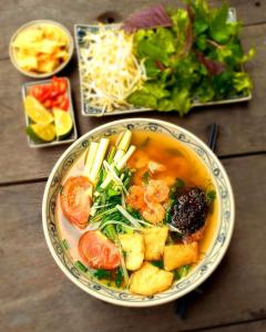 un tazón de sopa con verduras y una ensalada en Draha Halong Hotel en Ha Long