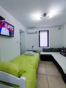 a bedroom with a green bed and a couch at Apartmani Park Mataruška Banja in Mataruška Banja