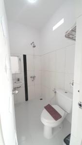 a white bathroom with a toilet and a sink at In Villa Garden Resort in Batu