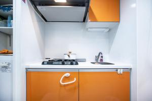 una cocina naranja y blanca con fregadero en Shinjuku Ryokan Retreat丶Local Tokyo Experience & Short Trips Hub丶walk to Higahsi Shinjuku station LoE2, en Tokio 17 fotos más