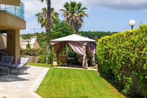 a garden with an umbrella and a lawn at Artemisia Villa, Sani Luxury Villas collection in Sani Beach