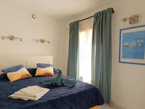 a bedroom with a bed with blue sheets and a window at Le Clos des Galéjades in Porquerolles