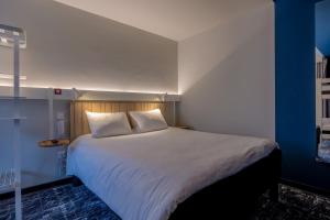um quarto com uma cama grande com lençóis brancos e almofadas em ibis La Rochelle Centre Historique em La Rochelle