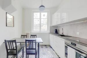 a white kitchen with a table and chairs in it at Le White Cozy - Lyon - Croix Rousse in Lyon