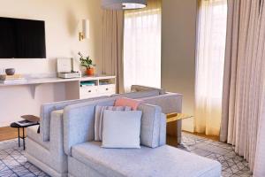 a living room with a couch and a tv at The Alida, Savannah, a Tribute Portfolio Hotel in Savannah