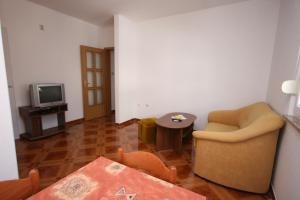 Sala de estar con silla, mesa y TV en Apartments and rooms by the sea Pag - 6311 en Pag