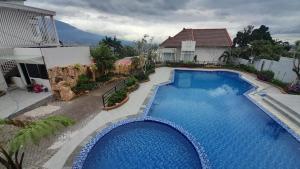 a large blue swimming pool in front of a house at In Villa Garden Resort in Batu