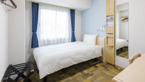 a small bedroom with a bed and a window at Toyoko Inn Osaka Namba in Osaka