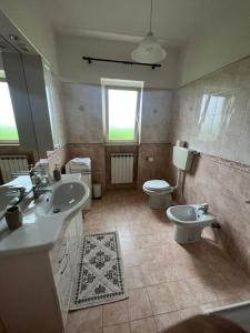 een badkamer met 2 wastafels, een toilet en een spiegel bij Villa Garibaldina in Treglio