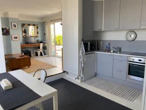 een keuken met witte kasten en een tafel. bij DERNIER ETAGE TERRASSE Pte St Coud in Boulogne-Billancourt