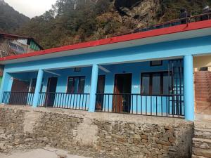 a blue house with a stone wall at King of Himalaya Homestay in Sari