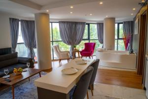 Parla Suite Hotel في إسنيورت: غرفة معيشة مع طاولة وكراسي وحوض استحمام