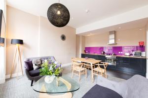 uma sala de estar com uma mesa e armários roxos em The Spires Serviced Apartments Edinburgh em Edinburgo