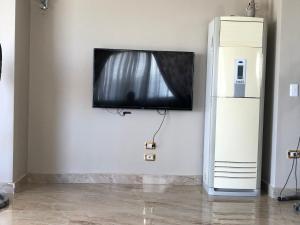 una TV a schermo piatto appesa a un muro accanto a un frigorifero di Senior chalet in Haciendabay for rent a El Alamein