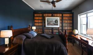 a bedroom with a bed and bookshelves filled with books at Adelaide Hills luxury cottage spectacular views in Summertown