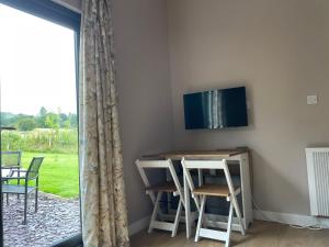 um quarto com uma mesa e cadeiras e uma televisão na parede em Beautiful self-catering cottages, Ribble Valley em West Bradford