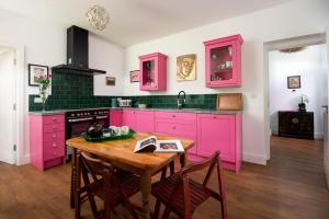 een keuken met roze kasten en een houten tafel bij Walltown Farm Cottage in Brampton