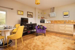 een woonkamer met een paarse stoel en een keuken bij Walltown Farm Cottage in Brampton
