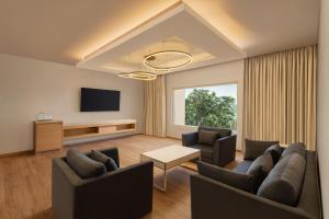 a living room with two couches and a tv at Courtyard by Marriott Tiruchirappalli in Tiruchirappalli