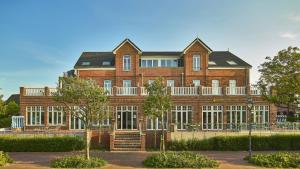 a large red brick building with a balcony at Lüttjeod Apartmentvilla Lüttjeod Apartmentvilla 06 in Langeoog