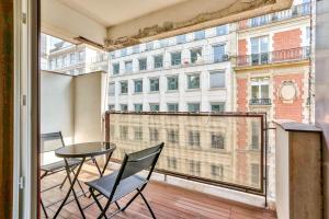 a balcony with a table and chairs and a large window at Appartement Quartier Arc de Triomphe Free Netflix in Paris