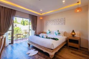 a bedroom with a large bed and a balcony at Vannee Golden Sands Beachfront Resort in Haad Rin