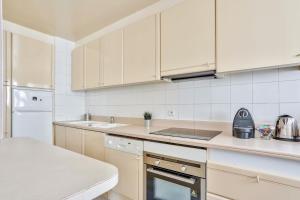 a kitchen with white cabinets and a counter top at Appartement Quartier Arc de Triomphe Free Netflix in Paris