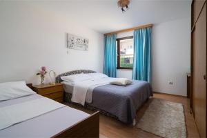 1 Schlafzimmer mit 2 Betten und einem Fenster mit blauen Vorhängen in der Unterkunft Apartments with a parking space Stanici, Omis - 2819 in Omiš