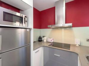a kitchen with red walls and a stainless steel refrigerator at Stay Barcelona - Castelldefels in Castelldefels