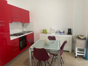 a kitchen with red cabinets and a table and chairs at Appartamento al centro di Scario in Scario