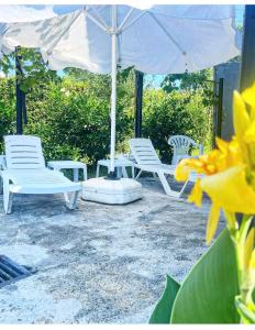 科布萊蒂的住宿－Зелёный двор，一组白色椅子、一把伞和鲜花