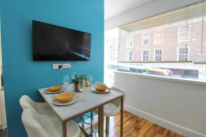 ein Esszimmer mit einem Tisch und einem TV an einer blauen Wand in der Unterkunft Stunning Central City Apartment in Nottingham
