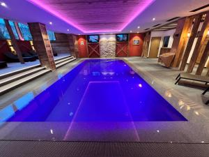 a swimming pool in a house with purple lighting at Hotel Olympia in Sarntal