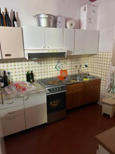 una cucina con armadi bianchi, piano cottura e lavandino di Domo Austinu - Abbasanta ad Abbasanta