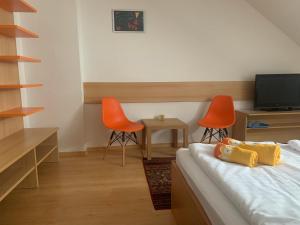 Habitación con 1 cama y 2 sillas de color naranja en Penzion Ludor en Strážnice