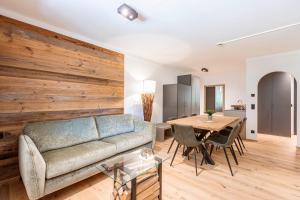 Saalbach Suites by ALPS RESORTS في سالباخ هينترغليم: غرفة معيشة مع أريكة وجدار خشبي