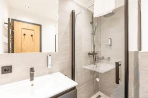 uma casa de banho com um chuveiro, um lavatório e um espelho. em Saalbach Suites by ALPS RESORTS em Saalbach Hinterglemm