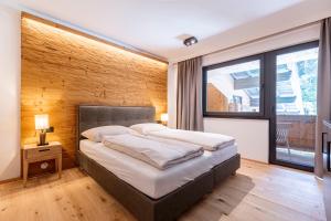 a bedroom with a large bed with a wooden wall at Saalbach Suites by ALPS RESORTS in Saalbach-Hinterglemm
