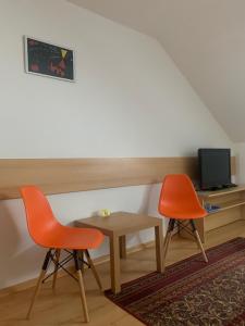 Habitación con 2 sillas, mesa y TV. en Penzion Ludor en Strážnice