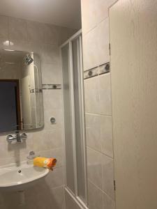 ein Bad mit einer Dusche, einem Waschbecken und einem Spiegel in der Unterkunft Penzion Ludor in Strážnice