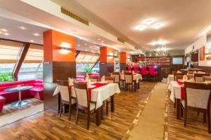 a restaurant with tables and chairs and red seats at Hotel Sipox in Štrba