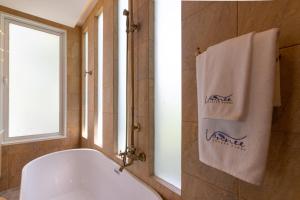 a bath tub in a bathroom with a window and a towel at Vannee Golden Sands Beachfront Resort in Haad Rin