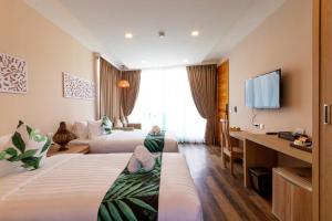 a hotel room with two beds and a flat screen tv at Vannee Golden Sands Beachfront Resort in Haad Rin +37 photos