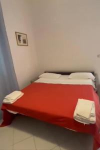 un letto rosso in una camera bianca con coperta rossa di Villa Donatella a Paestum