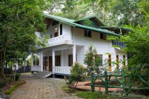 uma casa branca com árvores em frente em B'camp Resorts & Homestays em Wayanad