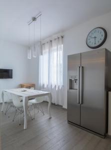 een keuken met een tafel, een koelkast en een klok bij La passione al mare in Marina di Massa